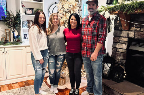 photo of Mother Cluckers owner Sabrina & family in front of Christmas tree & fireplace